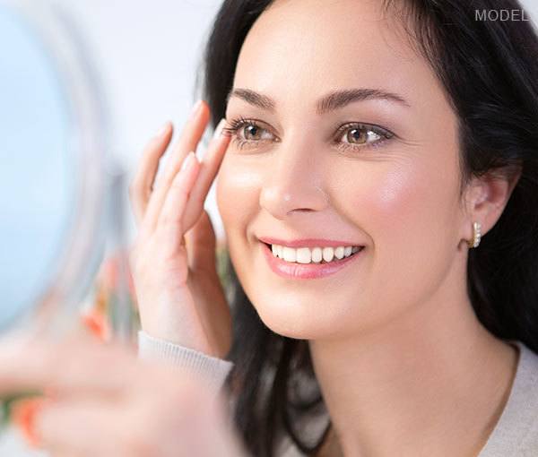 Model looking at eye lashes in mirror