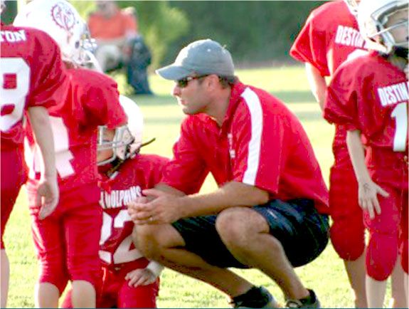 Dr. Edelman coaching youth football in a red jersey